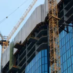 Crane konstruksi sedang membangun gedung pencakar langit modern dari baja dan kaca